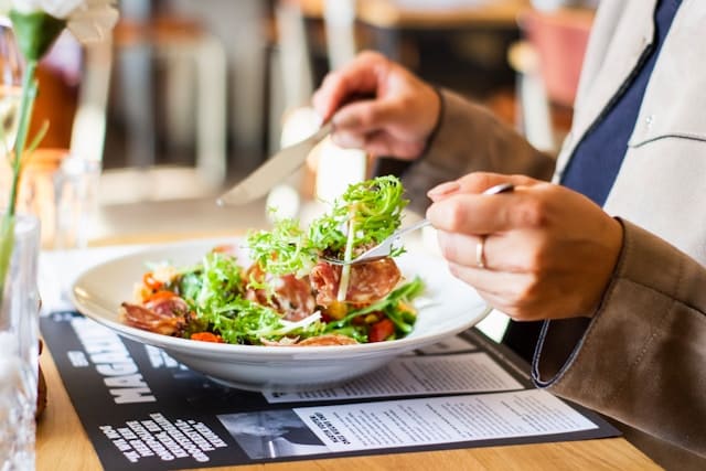 Zakelijk gekleedde vrouw eet een salade